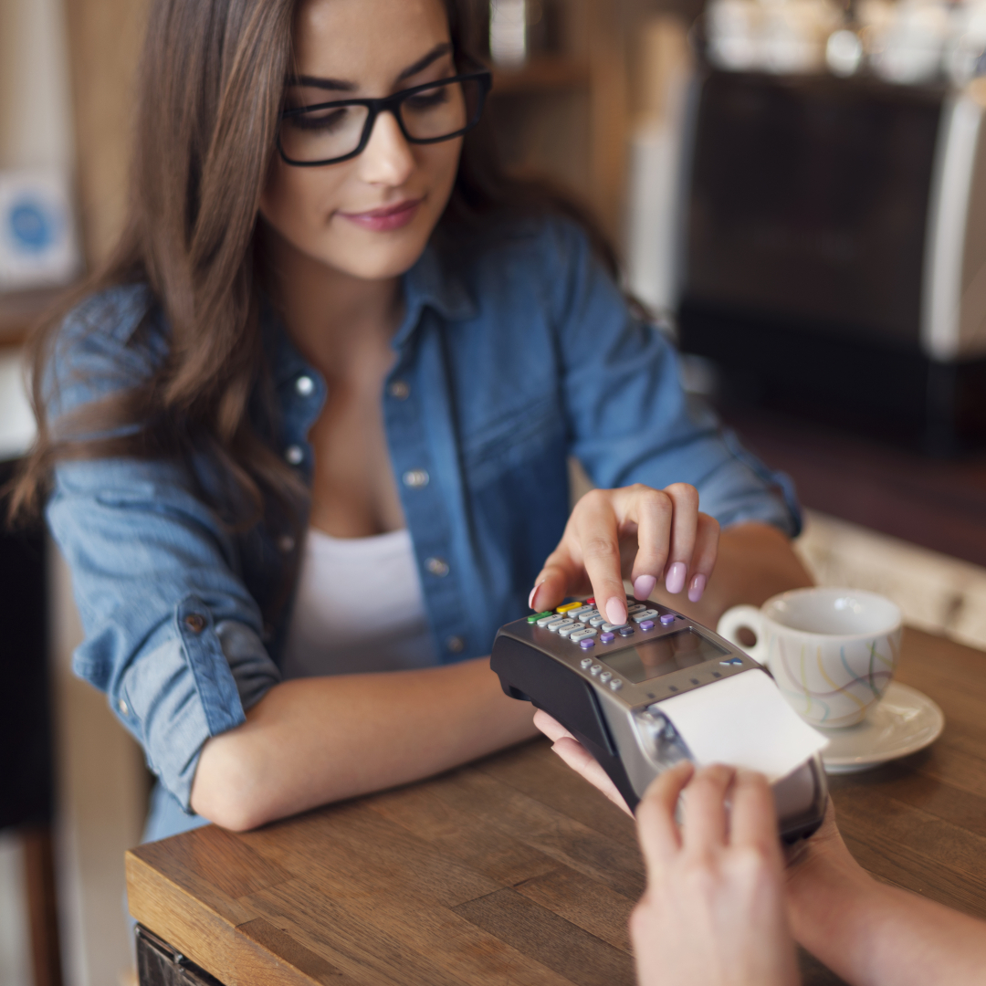 Mujer pagando con tarjeta en cafetería.